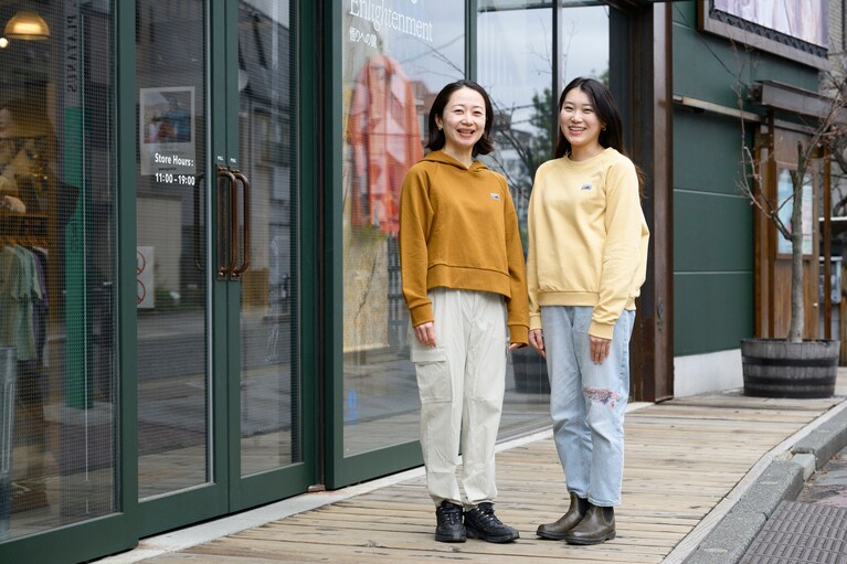パタゴニア東京・渋谷店のスタッフ・鍵山由起子さん（左）、中原美苑さん（右）が着用するスウェットには、「リジェネラティブ・オーガニック・サーティファイド・コットン」を100％使用。ラフに着られる軽やかなラグランスリーブ、短めの丈感が今の気分にマッチ。左／ウィメンズ・リジェネラティブ・オーガニック・サーティファイド・コットン・エッセンシャル・フーディ 14,850円　右／ウィメンズ・リジェネラティブ・オーガニック・サーティファイド・コットン・エッセンシャル・トップ 13,200円。