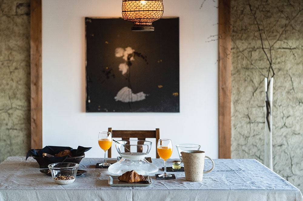2階にあるダイニングルーム。建てられた当時のままの土壁には、現代美術家である堀尾貞治の作品が飾られている。朝食は、搾りたてのオレンジジュースや、桑名発祥のこめ油を使ったオリジナルグラノーラなどが供される。