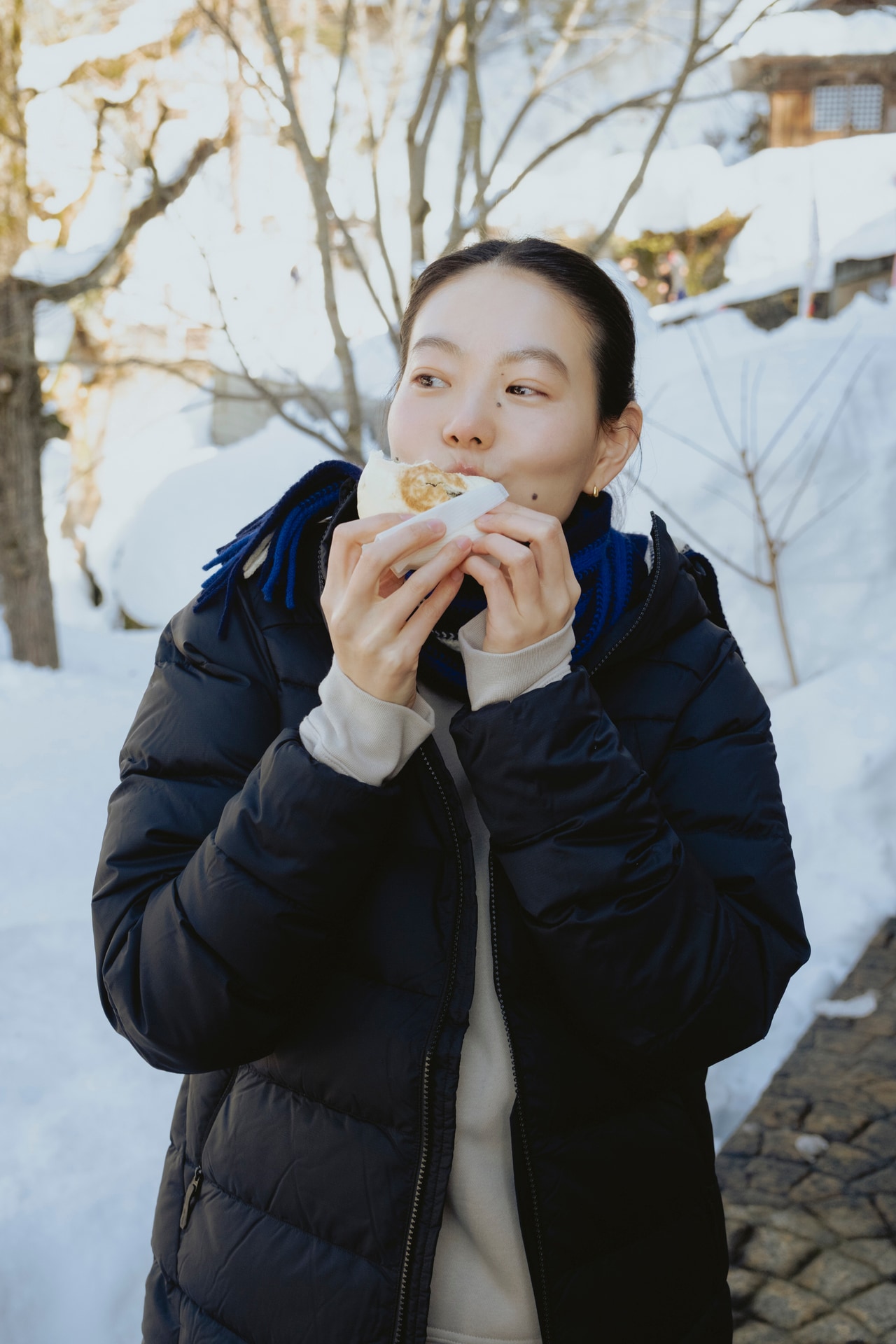 野沢温泉といえばこれ！　人気の食べ歩きグルメ「ハウスサンアントン」の野沢菜おやきを頬張る奈衣瑠さん。