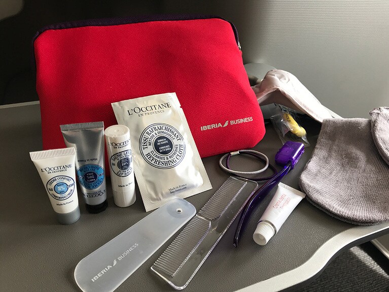 ロゴ入りの真っ赤なアメニティポーチに入っているコスメはロクシタン。クレンジングシート、フェイシャルクリーム、ハンドクリーム、リップクリームだ。ほかに、歯ブラシ、歯磨き粉、クシ、靴ベラ、アイマスク、イヤウイスパー、ソックス、脱いだ靴などを入れることができる収納袋が入っている。髪を束ねるためのゴムが入っているのも髪が長い女性には嬉しい心遣いだ。