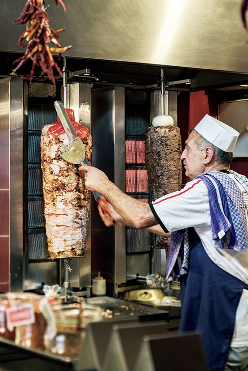 ドネルケバブは仔牛や鶏の肉をスパイスで味つけして回し焼きしたもの。削ぎ落としは手で。