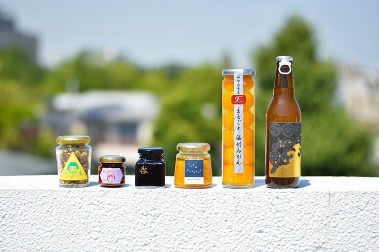 「彼女たちと語りたいガラスびん物語」のセット 6,000円(税込)。左から:S/S/A/Wの「エジプト塩」、S/S/A/Wの「モロッコ胡椒」、「旅するコンフィチュール」、FARM CANNINGの「ベジバーニャ ニンジン」、ふみこ農園の「まるごと温州みかん」、丹波ワイン「てぐみpeu」