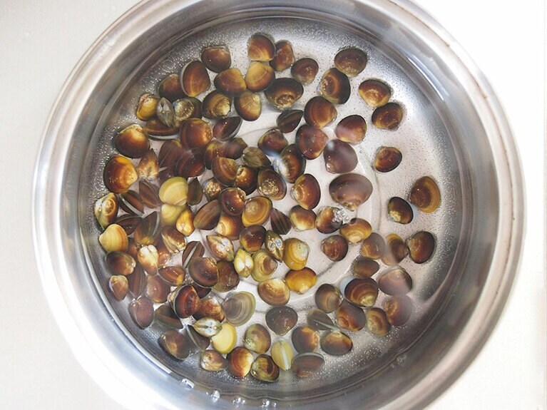 （2）砂出しをしたしじみをよく洗って、水と共に鍋に入れます。