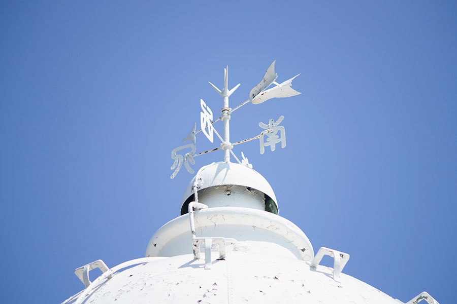 白い灯台と風見鶏が青空に映えている。