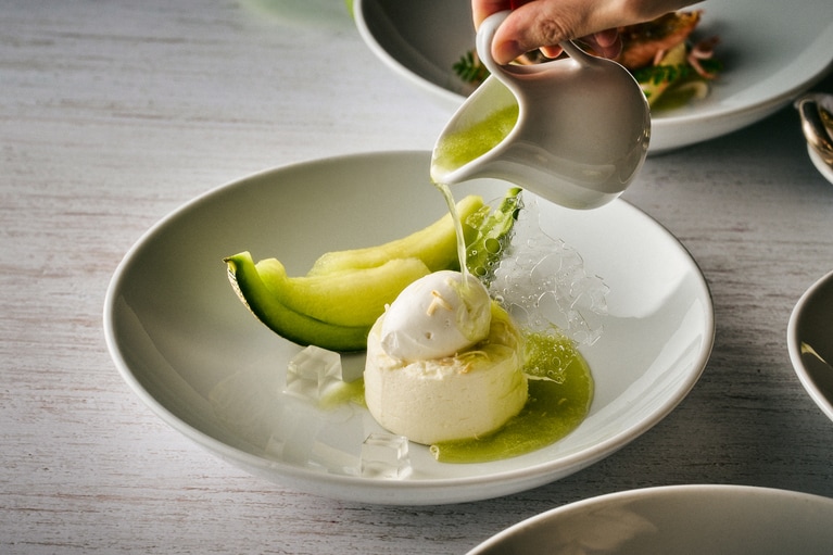 北海道産フロマージュブランのクレーム ダンジュに、茨城県産メロンのスープとココナッツクリスプを組み合わせたデザート。
