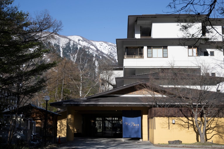雪の名残が山肌を彩る絶景を背負い、和情緒たっぷりに佇む宿。