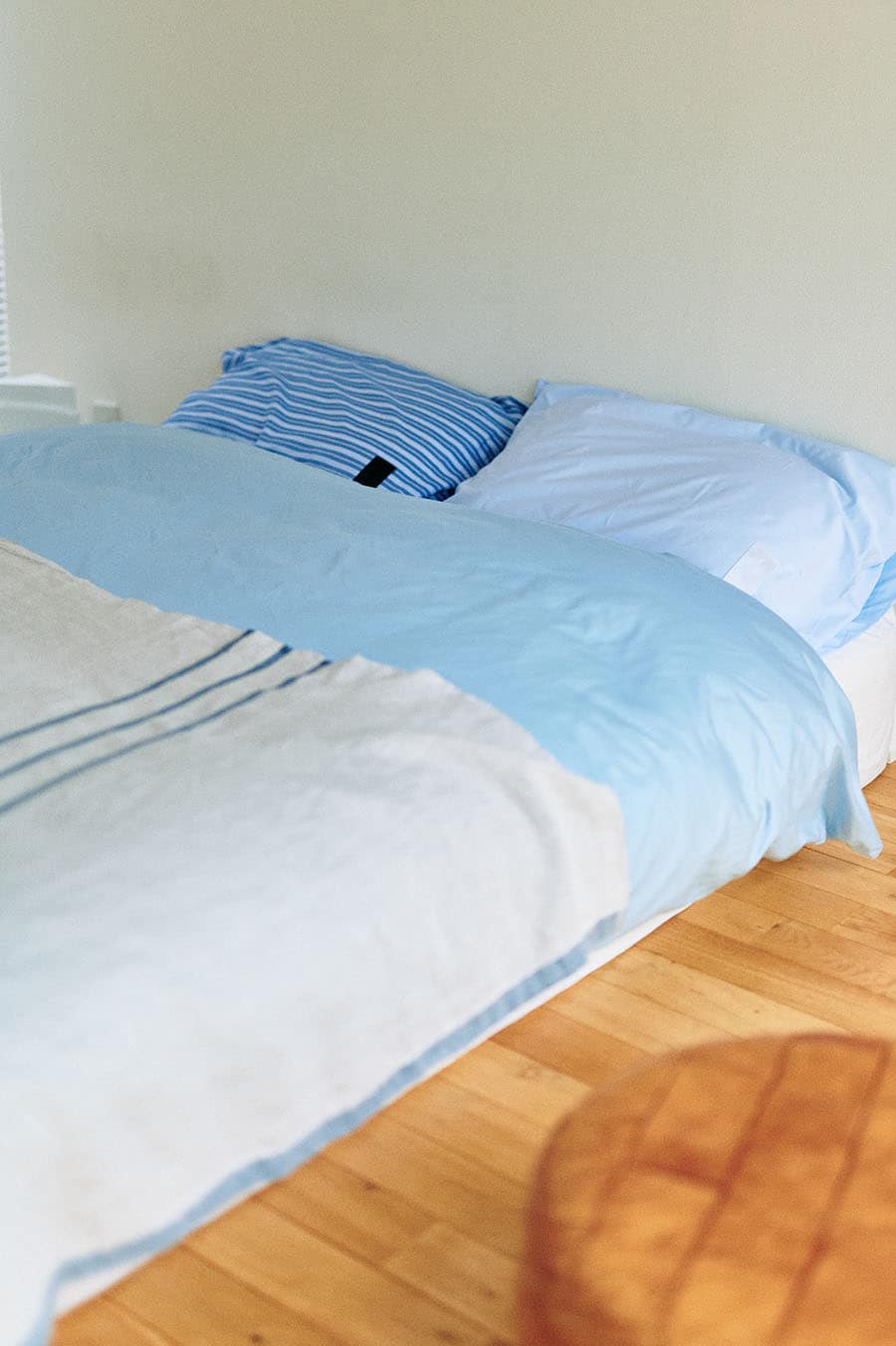 ベッドリネンは寒色系でコーディネート。ベッドスローに使っているのは、柔らかな素材感で寝室に優しさをプラスするブランケット。