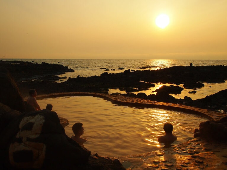 海辺の露天風呂から望む美しい夕景を求めて全国から人々が訪れる。夕方は混み合うが、朝は比較的空いていて、のんびり入浴できるそう。悪天候時は利用不可。