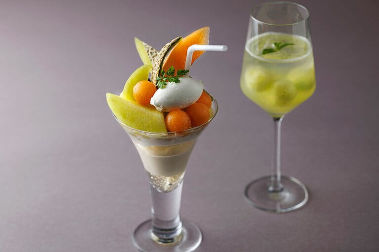 「メロンパフェ」4,300円。「メロンスカッシュ」（写真奥、単品 2,200円）とのセットは6,000円。コーヒーまたは紅茶とのセットは5,700円。1日10食限定、予約不可。