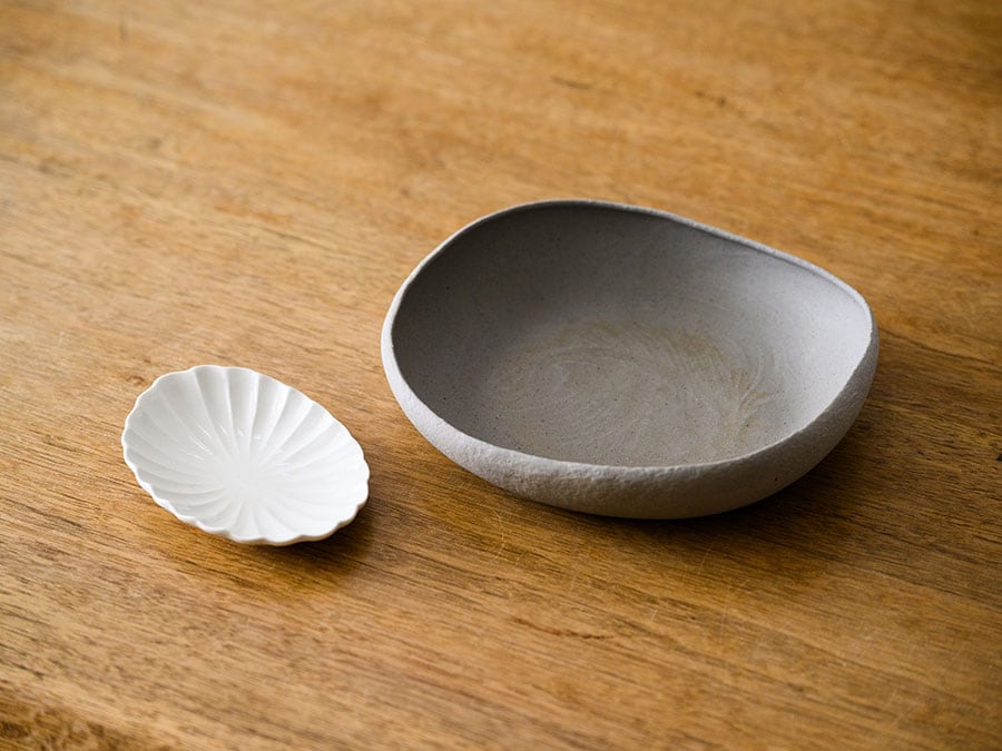 渡辺隆之さんの楕円鉢（写真右）は軽くて使いやすく、カレーや煮物のほかパスタ皿としても使いやすい。角田淳さんの輪花皿（写真左）は薬味や漬物を盛れば、食卓のいいアクセントに。