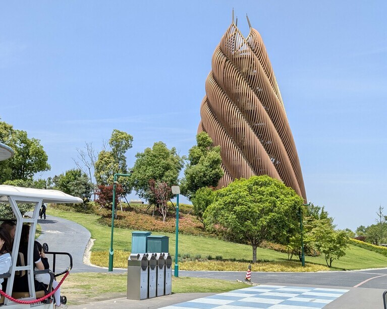 成都基地で、近年拡張された新エリア。アドベンチャーワールドで生まれたパンダの多くは新エリアにいる。写真左は有料のカート、右にそびえるのは「熊猫（パンダ）塔」（タケノコタワー）。2025年4月30日（水）。