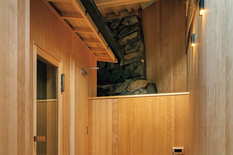 外気浴スペースには、隣接した歴史あるお寺の石垣がそのまま残されている。掛け流しの水風呂は冬は水温が1桁台に。（BYAKU Narai かね上屋　長野）