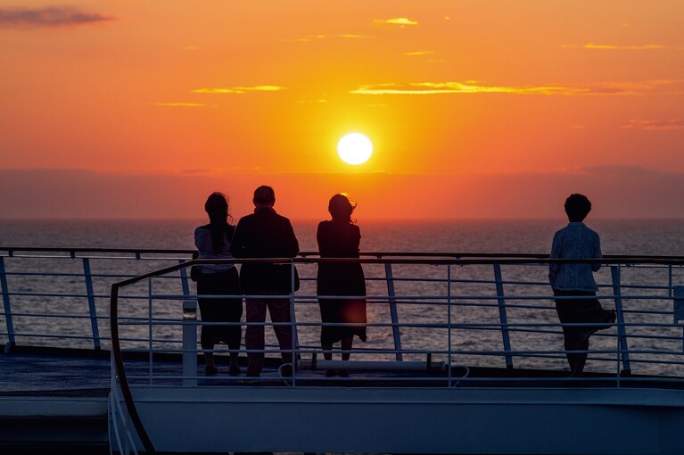 夕陽に見入る人々。海を染める、洋上の夕景。