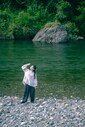 夏の穴吹川には、水遊びを楽しむ人で賑わう。遠くまでよく見える、ひらけた空間が気持ちいい。リネン天然染めギャザーブラウス（OFF WHITE）30,800円、リネンデニムワイドジーン（BLACK）33,000円