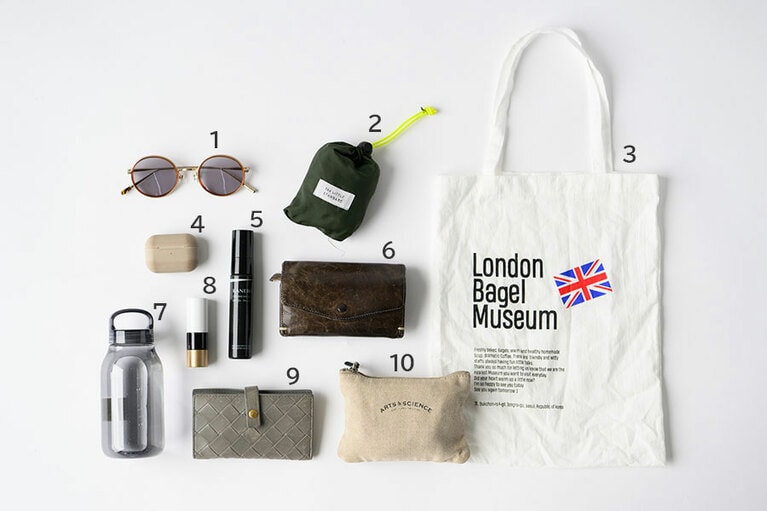 1：自転車の日にマストな「ブラン」のサングラス。2：キッズウエアのショップ「ザ・リトルスタンダード」のエコバッグ。3：韓国土産でもらった「ロンドンベーグルミュージアム」のトート。「小さいショルダーを持つときには、バッグは基本2個持ちです」。4：娘が小学校に入り、一人時間が増えたので、エアポッツは必需品。5：「カネボウ」のミストUV。顔、体、頭皮などに気軽にシュッとできるうえSPF50＋という優れもの。6：8年ほど愛用している「アーツアンドサイエンス」の財布。使い込むほどにレザーの味が増していく。7：常温派にぴったりのシンプルなボトルは「キントー」。8：友人からもらった「エルメス」のリップ。「顔色が明るくなるコーラルカラーが気に入っています」。9：新居に越したのを機に「ボッテガ・ヴェネタ」のキーケースに新調。シックなグレーに一目惚れしたそう。10：「アーツアンドサイエンス」のポーチに、絆創膏やヘアピンなど娘さんの持ち物をまとめて。