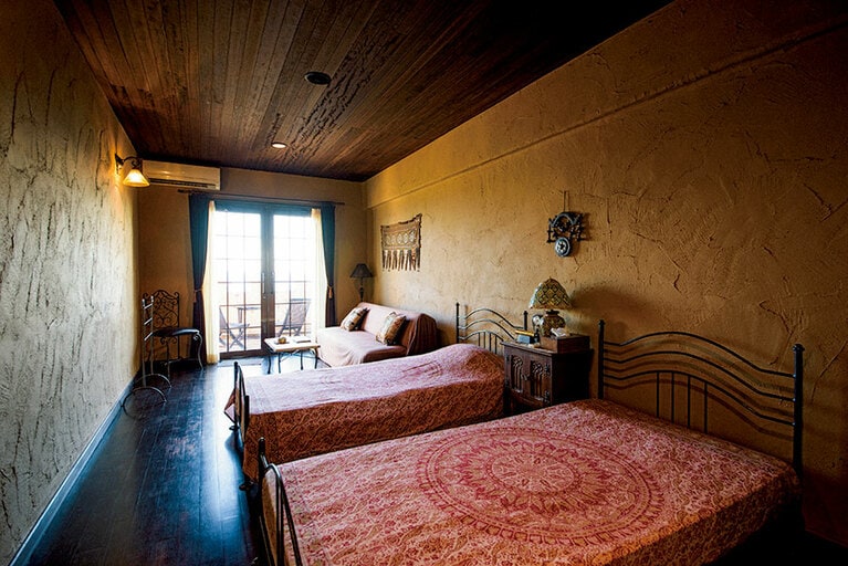インド更紗のリネンが心地いいゲストルーム。館内の元シタール奏者のオーナー厳選の調度品が、非日常感を演出してくれる。