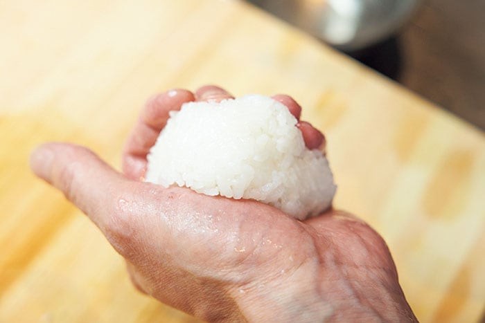 ご飯をのせている手は親指のつけ根と残りの4本の指でご飯をはさむ。