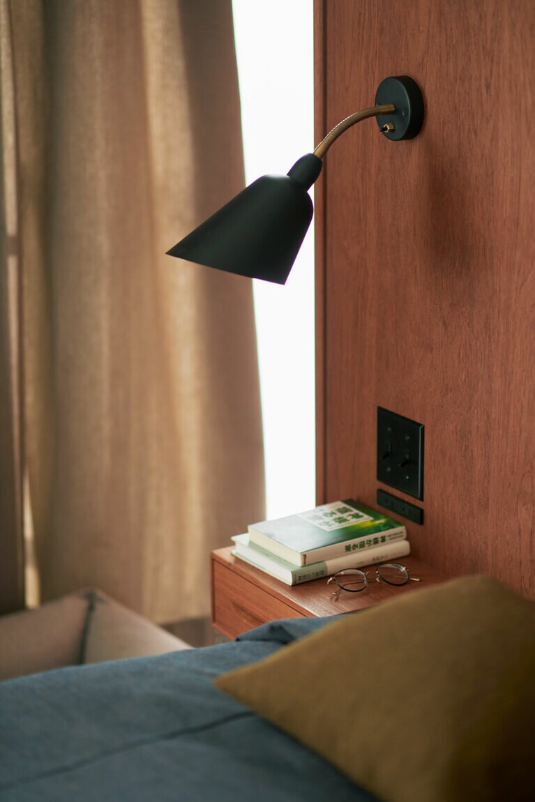 ベッドに入ったら本を読む。読書灯には角度を自由に変えられる北欧の「ベルビューウォールランプ AJ9」。