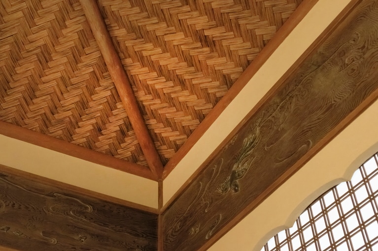 建物内には、杉板を薄く切って編んだ「網代天井」（写真）や、5センチもの厚さの板を彫刻刀で手彫りした「透かし彫り」など、当時の職人技が随所に息づく。