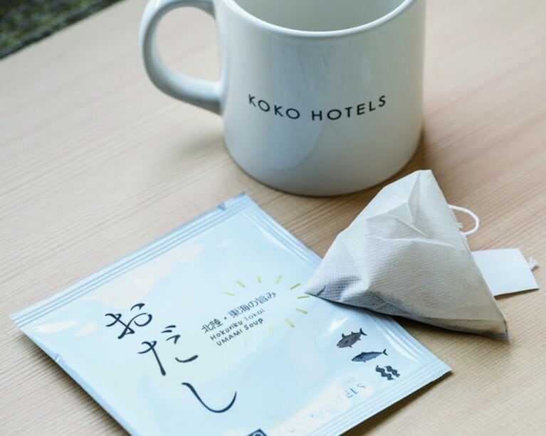 【うれしい「お出汁パック」サービス】フロントで手渡されるオリジナルの「お出汁パック」。KOKO HOTELSならではのこのおもてなしには、“ここから見つける旅を。” をコンセプトとするホテルの想いが凝縮。金沢香林坊では昆布ベースの出汁を提供し、鰹節ベースなど、地域によって異なる5つの味を用意しています。