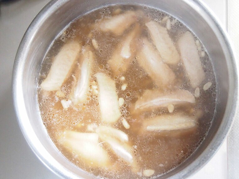 鍋に水 （800cc）、手羽中肉、松の実、醤油、調理酒を入れて弱火で加熱する。