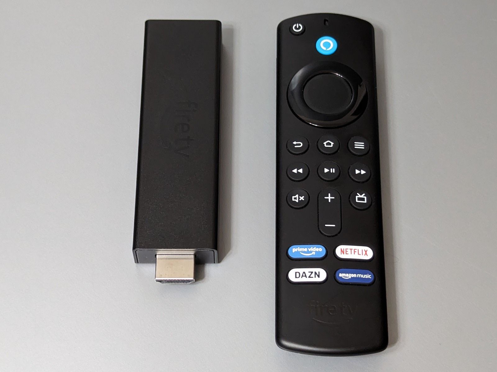 「Fire TV Stick」。本体（左）をテレビのHDMIポートに挿入して電源ケーブルを接続、続いてWi-Fi設定を行うことで、AmazonプライムビデオやNetflixなどの動画配信サービスをテレビで楽しめるようになります。操作にはリモコン（右）を使用します