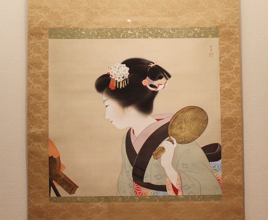 上村松園《鴛鴦髷》(1935年)。結った髷を合わせ鏡で確かめる姿が愛くるしい。
