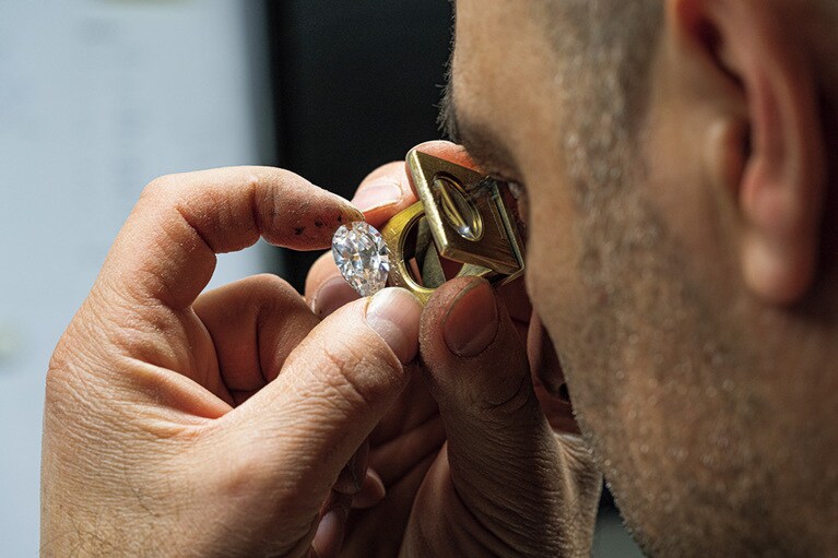 ダイヤモンドのファセットの品質チェックを行う職人。