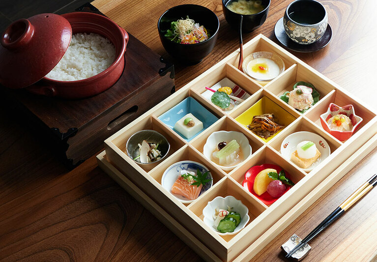 土鍋で炊き上げた「特Aさがびより」の釜炊きご飯と、十数種の彩小鉢がセットになった朝食のイメージ。