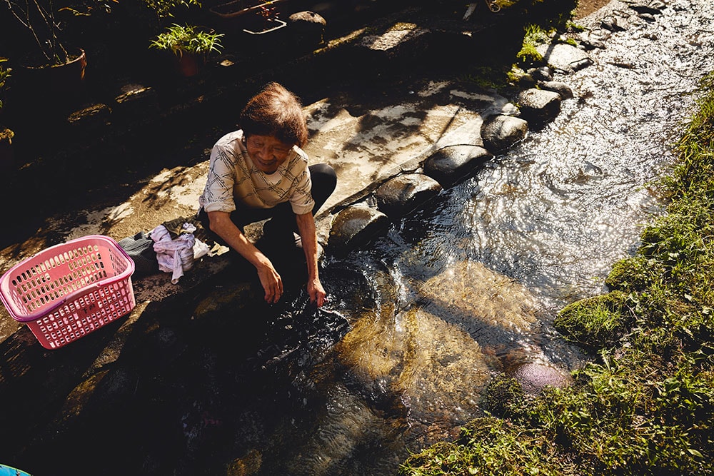 川で洗いものをするおばあさん。この水辺の小さな空間は、洗場組合によって自主的に守られてきた大切な場所。