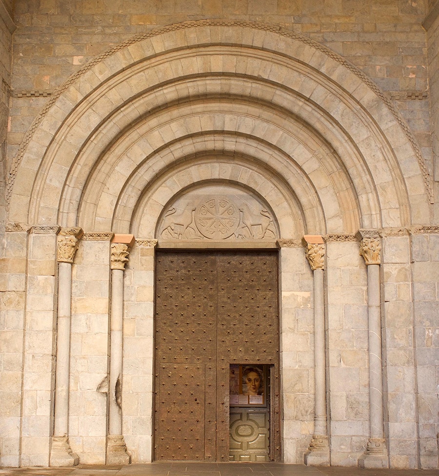 大聖堂の西にある「荘厳の入り口」。扉上のアーチに囲まれたタンパンに施された装飾は、象徴的かつ重要な意義あるものとされた。左の柱下にあるのが、巡礼者たちが触れたことでできた窪み。扉を囲むアーチの最外周にチェックが施されているが、これは“ハカチェック”といわれ、巡礼のシンボルであるホタテの代わりに使われている。