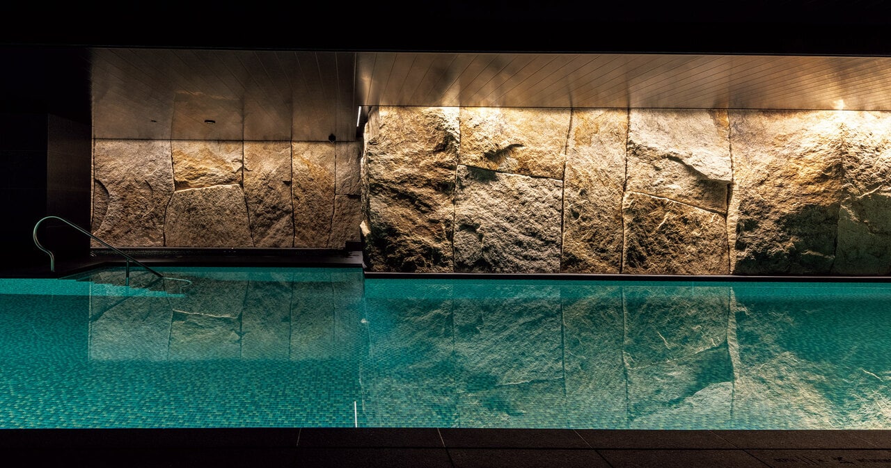 地下1階プール。壁面を覆うのは岡山県産の北木石。表面に磨きをかけず質感を残した。