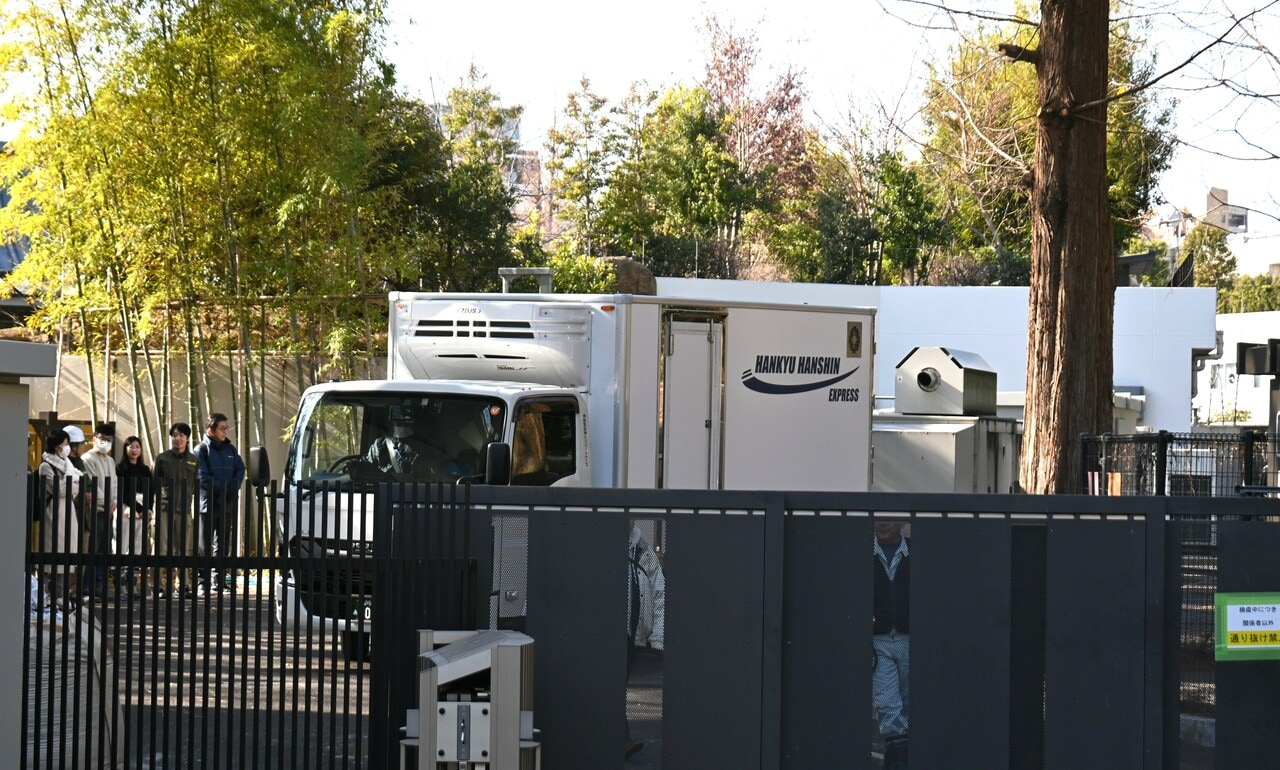 職員（写真左）に見送られながら、双子は生まれ育った「パンダのもり」を出ていった。扉には「検疫中につき 関係者以外 通り抜け禁止」とある。（2026年1月27日、園内の報道関係者用のエリアから筆者撮影）