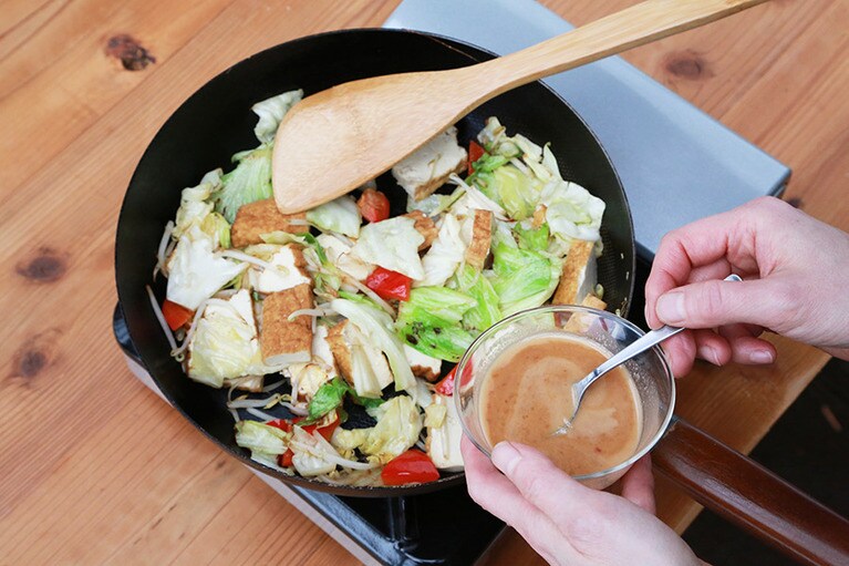 全体に油が馴染んだら火を弱め、調味液を加えて具材全体に絡ませる。