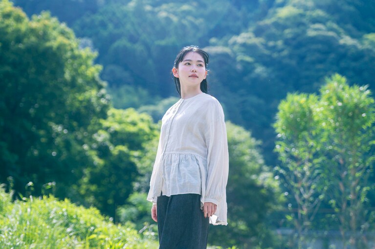 バックが長めのブラウスは、風に吹かれて軽やかにひるがえる。