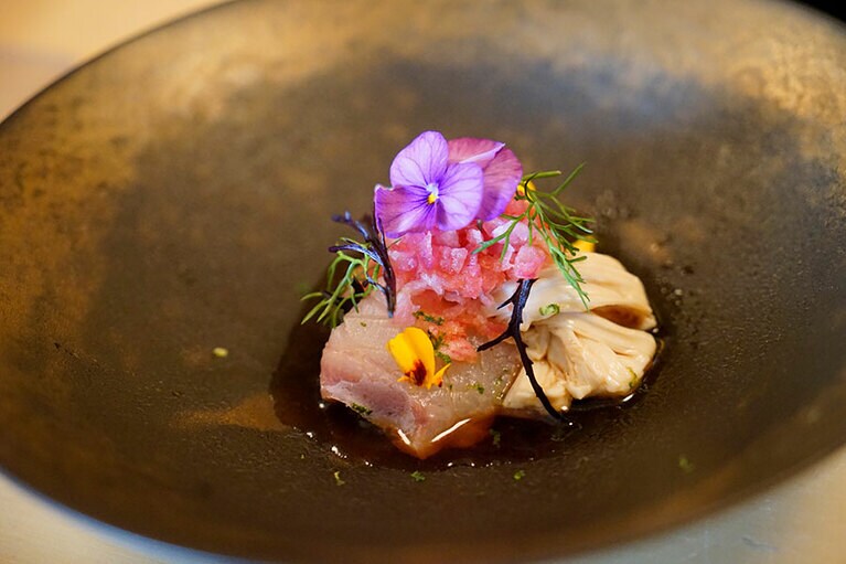 握りの前にいただくおつまみの中には、下條さんならではの和洋折衷のものも。こちらは、朝獲れのブリとクエに湯葉や辛味大根やスダチなどを加え、マリーゴールドとスミレの花が添えてある。