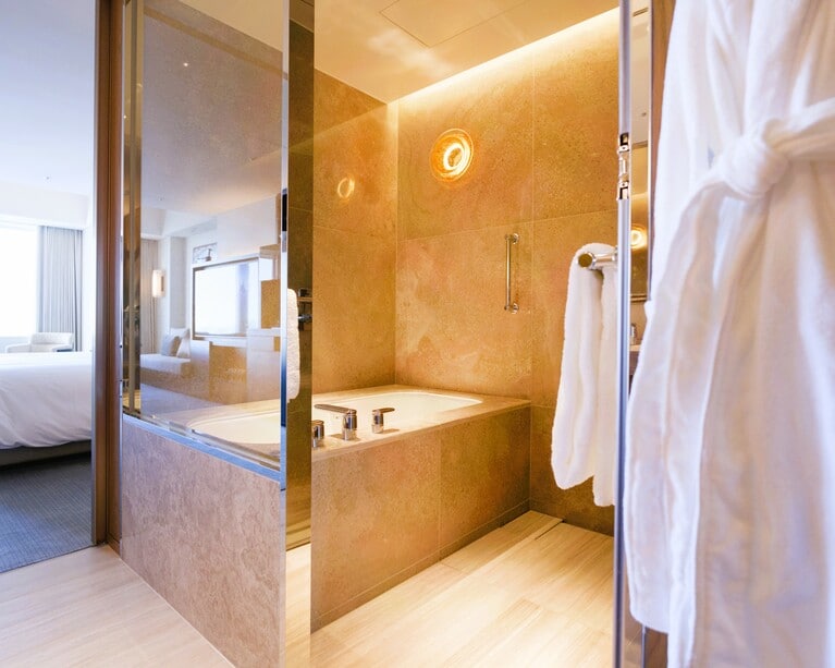 バスルームは、日本の浴室から着想を得たゆったりとした空間に。バスリネンは、イタリアの最高級ブランド「FRETTE（フレッテ）」。幸せな肌触りに気分が高揚し、用意された季節のバスソルトもうれしい。