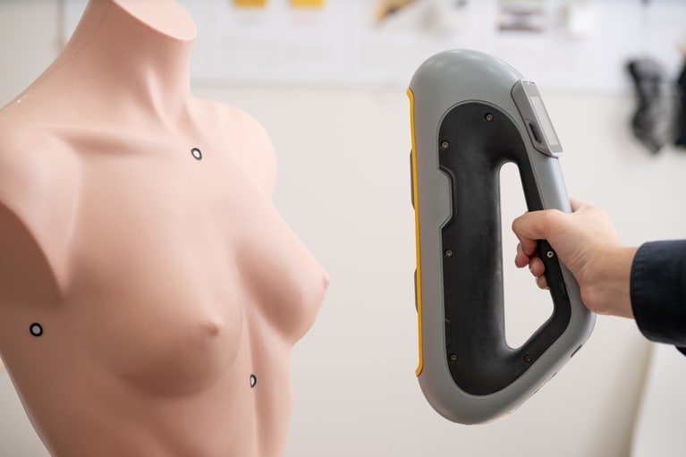 各店舗に用意されている3Dスキャナーはハンディタイプ。お客様の肌に触れることなく5～10分で測定が可能。術前の乳房を3Dスキャナーの測定データとして残しておくこともできる（別料金）。※測定の様子をマネキンで再現。