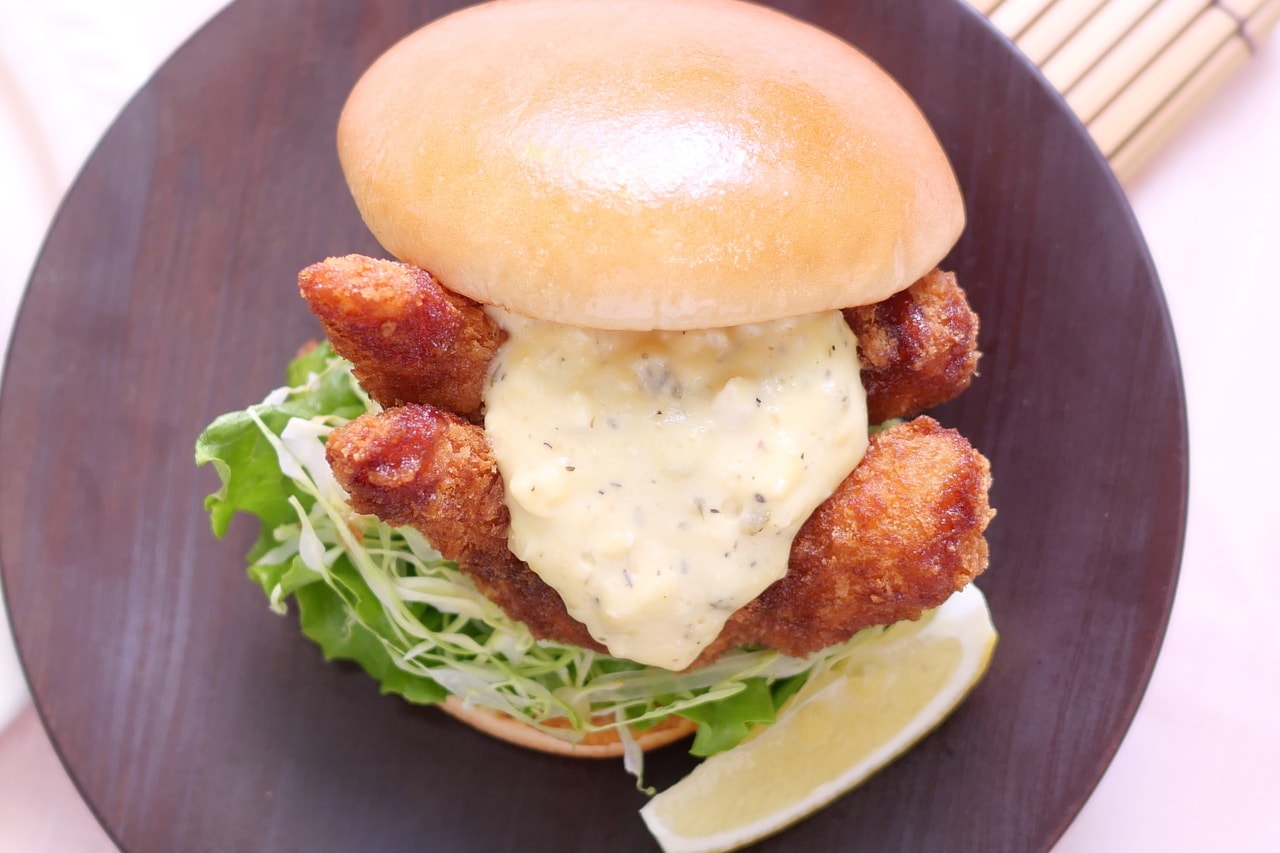 ドローンの視点から「『モスの匠味』海老エビフライバーガー ～くし切りレモン添え～」を見ると、思いっきりバンズからはみ出した2本の海老がよくわかる。