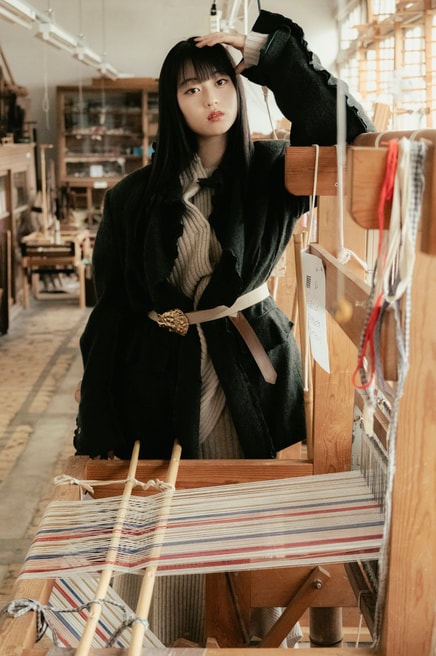 建物内では秩父銘仙の歴史や展示品を見ることができるほか、型染めや織りの体験も可能。木製の織り機や設備はすべて現役で使われているので、職人が織りを行う姿に出会えることも。菊池さん着用：ターギー フォー ウォータープルーフ ¥24,200／キーン（キーン・ジャパン）、ジャケット 96,800円、ベルト 36,300円／共にフミエタナカ（ドール）、ニットトップス 57,200円、ニットスカート 52,800円／共にオープン セサミ クラブ バッグ 37,400円／ルメメ、タイツ／スタイリスト私物