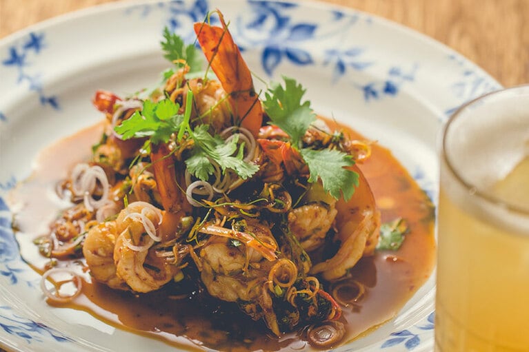 「香茅拌蝦」420元は、レモングラスたっぷりのソースで、すっきりとした辛さのえびのサラダ。手前右のカクテルは「GALANGAL DARK RAM」280元。ガランガルはショウガの一種でハーブとして使われる。