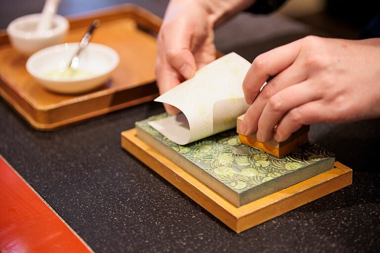 版木に絵具をのせ、和紙をかぶせて文様を写し取る。