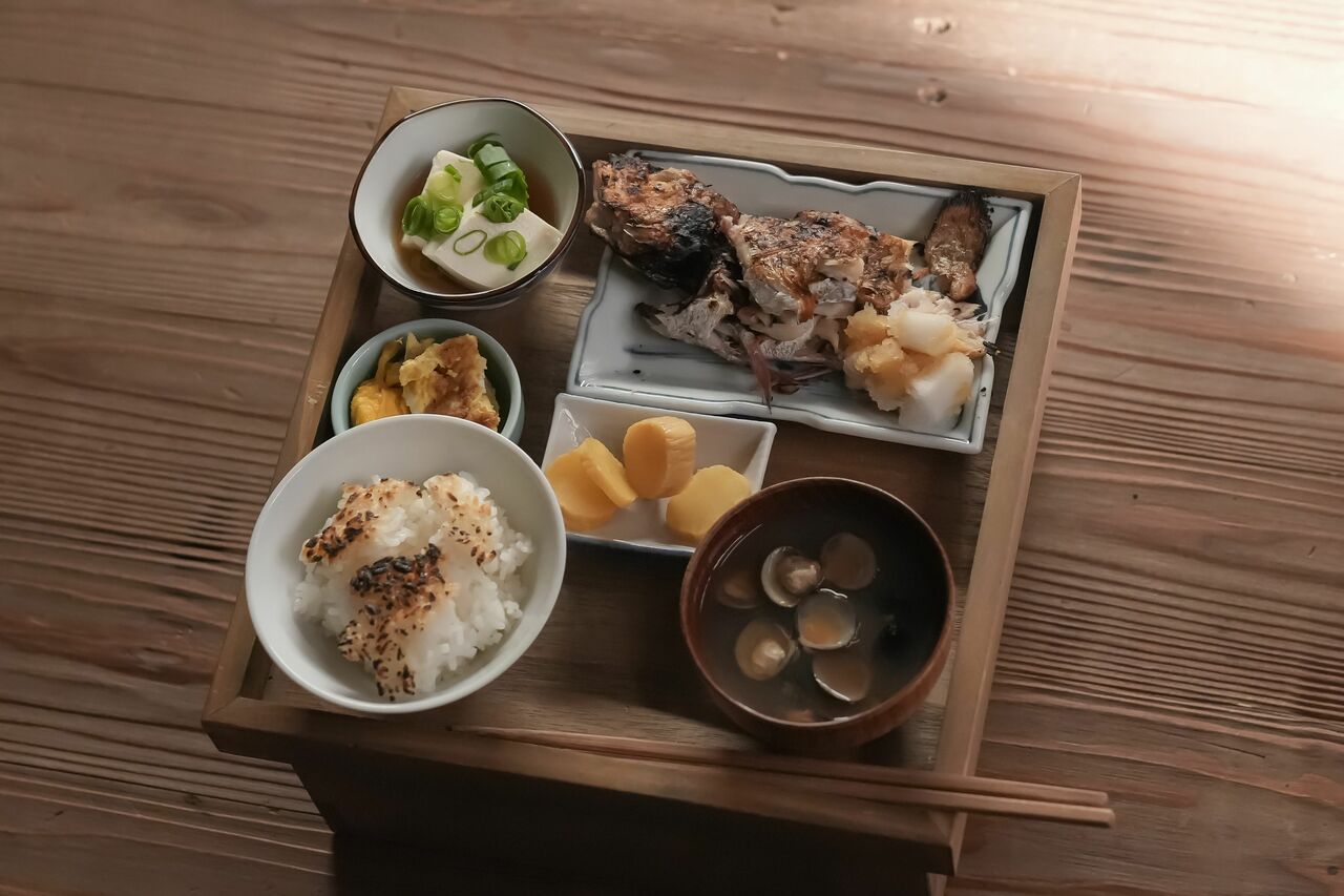 タエ（北川景子）が不器用な手つきで作った昼餉。当時は庶民にとって身近な魚だったノドグロを塩焼きに……だが網に引っついて焦げてしまった。ごはんについた大量のおこげ、大根おろしに混じった大きめの塊の大根、ねぎの雑な刻み方など芸が細かい。「タエさんの最終出演シーンでもほとんど同じ献立。料理が上達したという設定で作ったのが感慨深かったです」と広里さん　（C）NHK