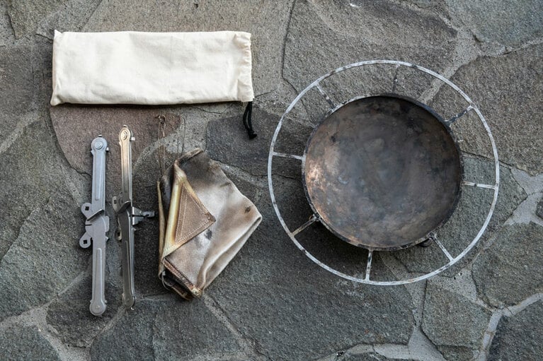 左は折り畳み式の焚き火台。バックパックに入る収納サイズ。ワイヤフレーム W36 cm×H28 cm 18,480円／モノラル　右はタキビズム リアル ファイヤースタンド ジカビ Mサイズ W約40×H約7cm(パンの直径：約27cm ※取り外し可能) 17,600円／UPI