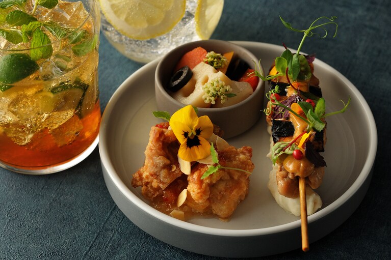 「OMOカフェ＆バル」の夜限定メニューは、五反田の鶏肉専門店「信濃屋」の唐揚げと焼き鳥をアレンジした「おつまみプレート」1,000円。オリジナルのアルコールドリンク800円～。