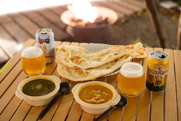 焚き火を眺めつつ、ネパールカレーの「サジロカフェ リンデン」2人分セット 3,680円。ビールはホテル内のカフェから。