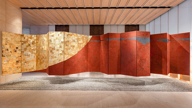 悠久の情景を感じさせる月と玄界灘の情景を、屏風という伝統的な型式で表現した作品。展示場所：1階・18階エレベーターホール　素材：ベンガラ、鉄、銀箔。