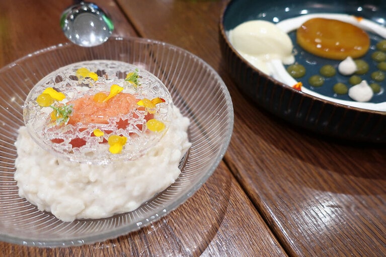 スペイン・アンダルシア地方のデザート「トチーノ・デ・シエロ」（左）は、濃厚でクリーミー。「ココナッツ・アロス・コン・レチェ」（右）は、バスク・チーズケーキの周りに、バニラのショートブレッド、ラズベリーとホワイトチョコレートのガナッシュ、ピスタチオが添えられている。どちらも55ディルハム。