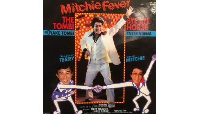 三橋美智也「Mitchie Fever」。プロデュースを手がけたのは、テリーこと寺内タケシ。マルちゃん「激めん」のCMでは、この白いスーツ姿で「激れ！ 激れ！」と叫んでいた。ミッチーは民謡三橋流の家元でもあり、細川たかしは、その弟子としては「三橋美智貴」を名乗っている。