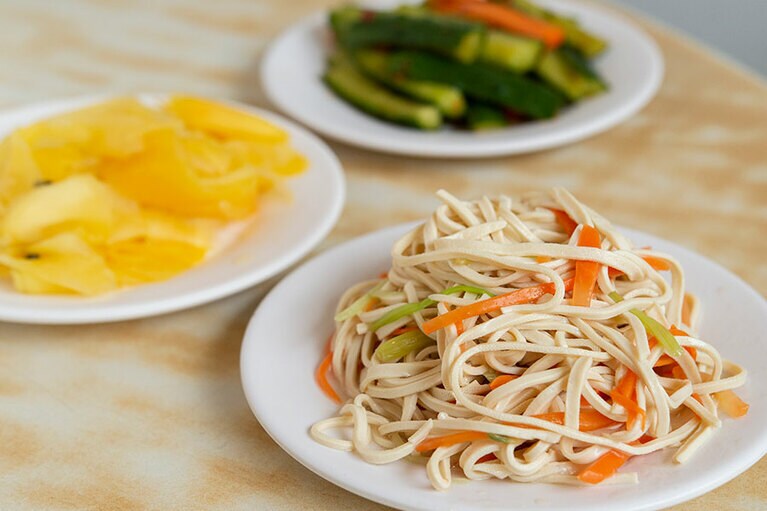 ［黄龍荘］手前から時計回りに：干し豆腐、甘めに味付けしたパパイヤ、ピリ辛のキュウリ。小菜は一律40元で、冷蔵庫から自由に選ぶ。ピータン豆腐や白菜の漬物も定番。